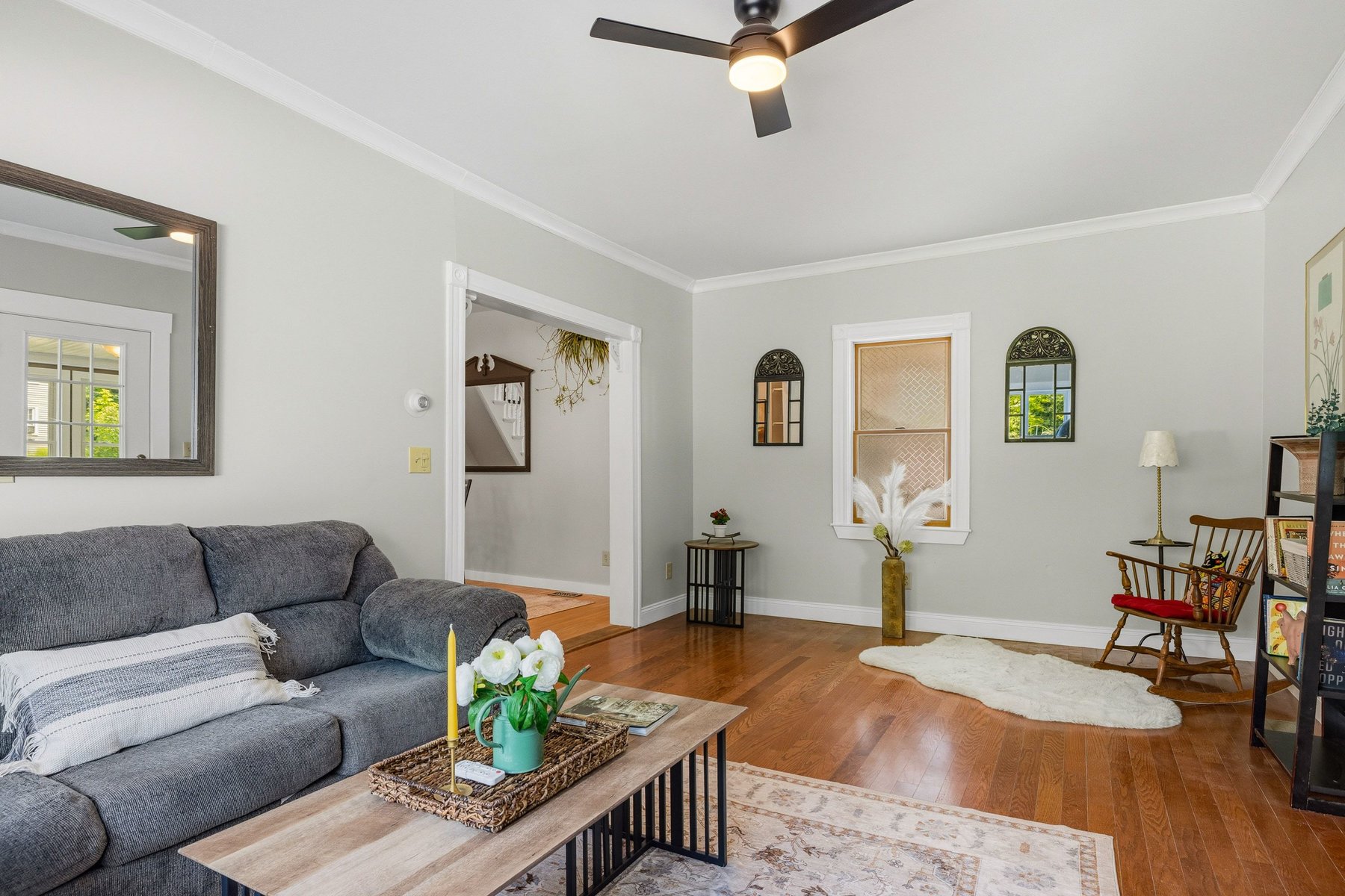 Historic side living room with warm oak floors, crown molding and abundant natural light