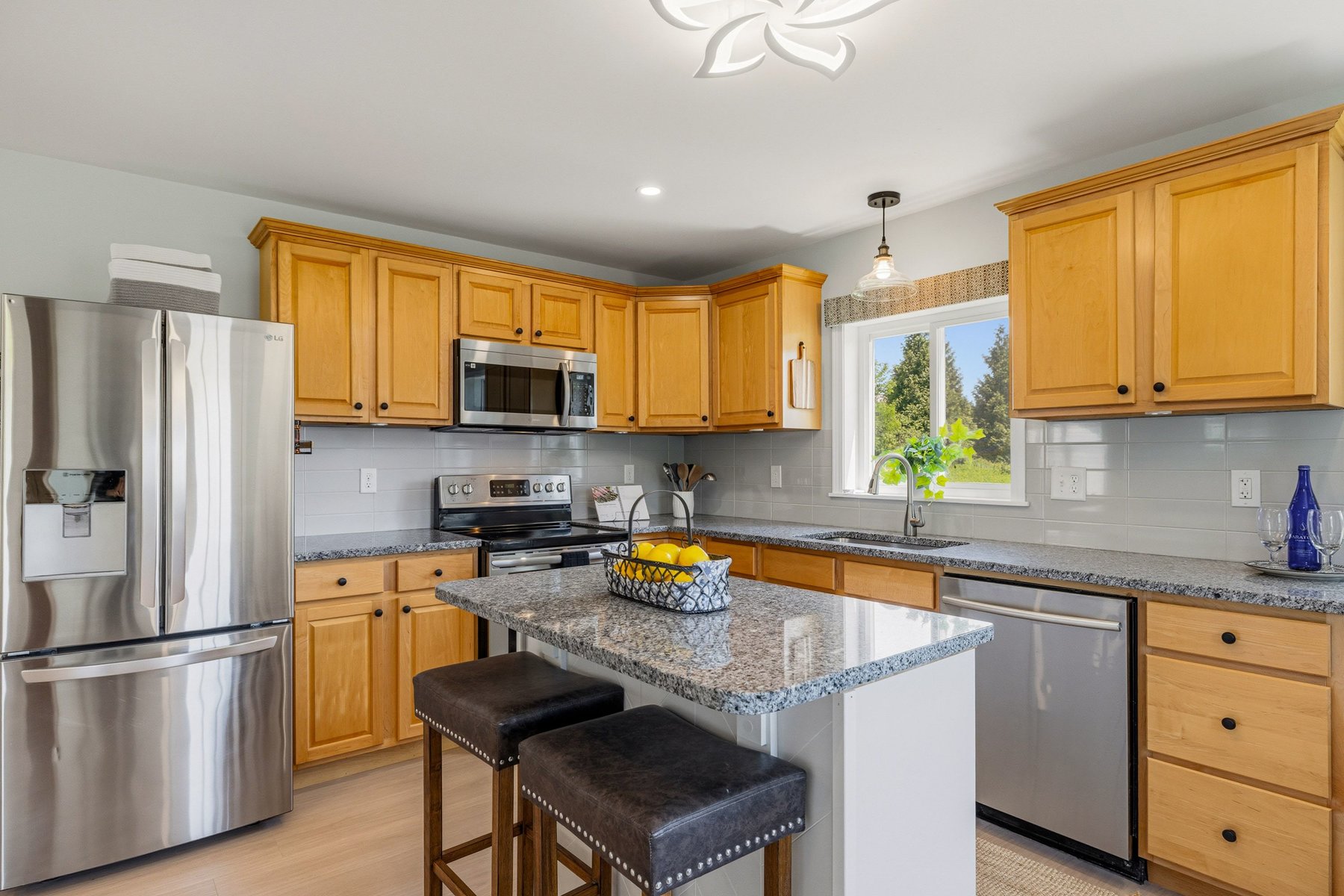 Bright new-build kitchen with maple cabinetry, granite counters, stainless appliances and a center island