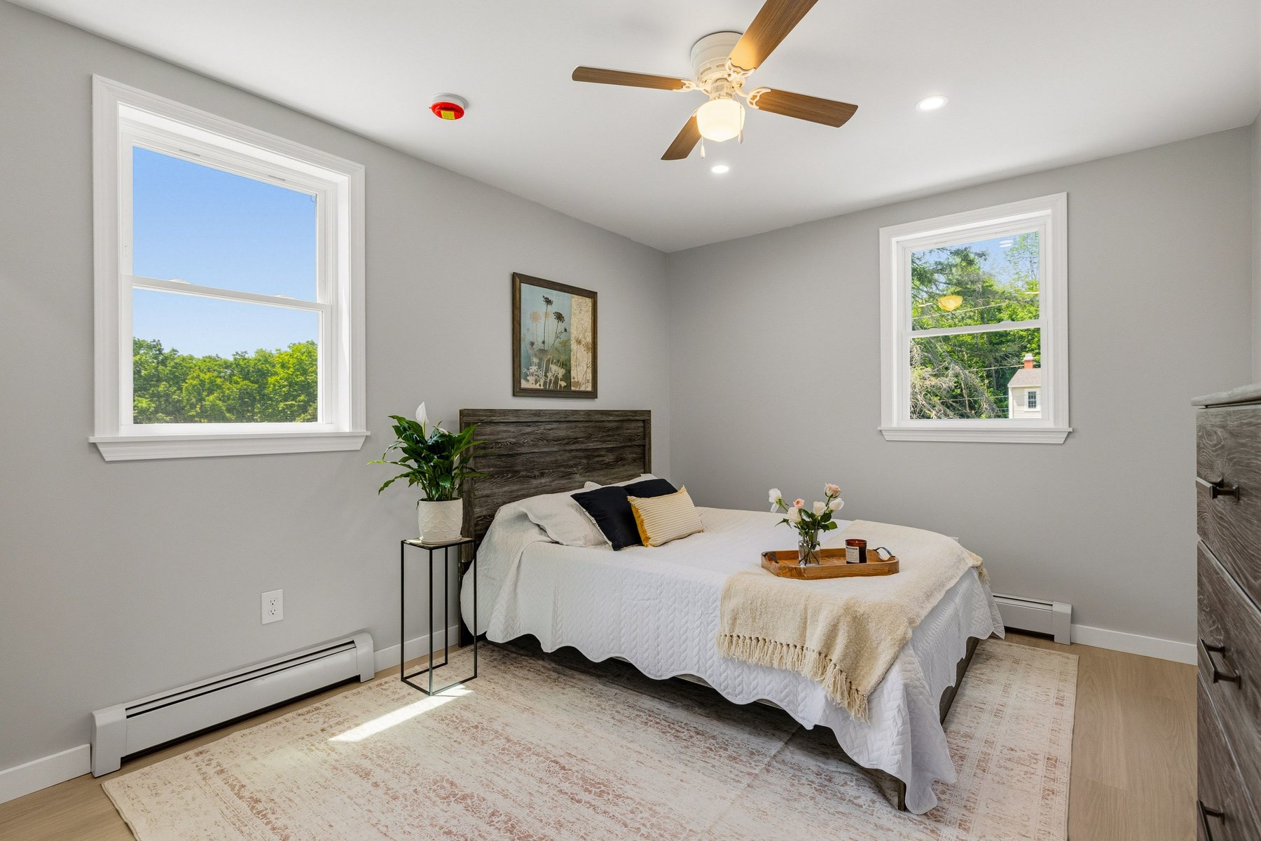 Staged primary bedroom on Side A with ceiling fan, big windows and treetop views