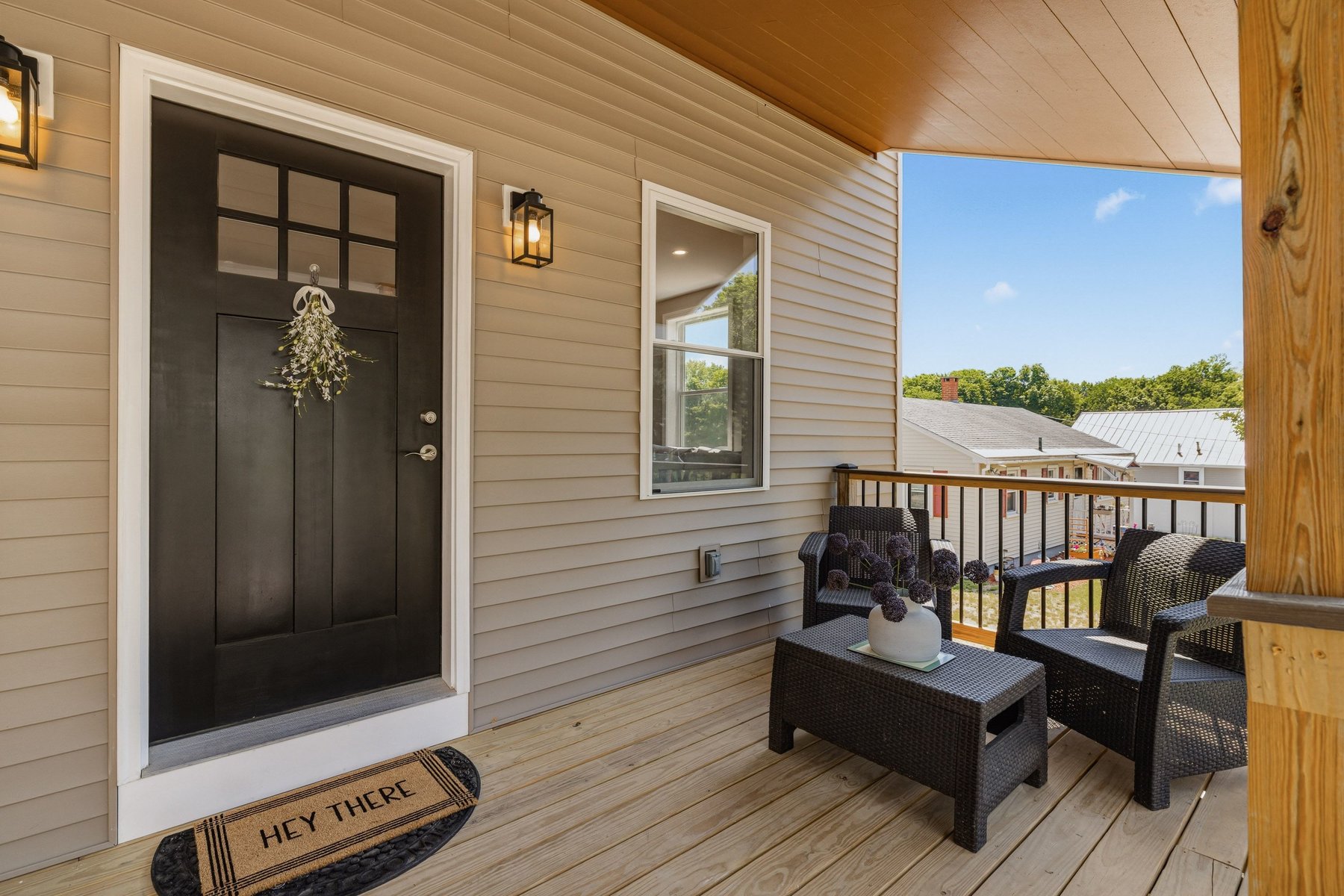 On Side A's farmer's porch — black front door with wreath and wicker seating